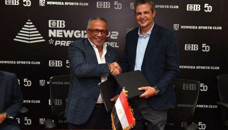 صورة توقيع اتفاقية تعاون بين البنك التجاري الدولي CIB ونادي نيو جيزة الرياضي، يظهر ممثل الجهتين أثناء المصافحة وتبادل الوثائق، مع شعار CIB ونادي نيو جيزة في الخلفية وعلم مصر في المقدمة